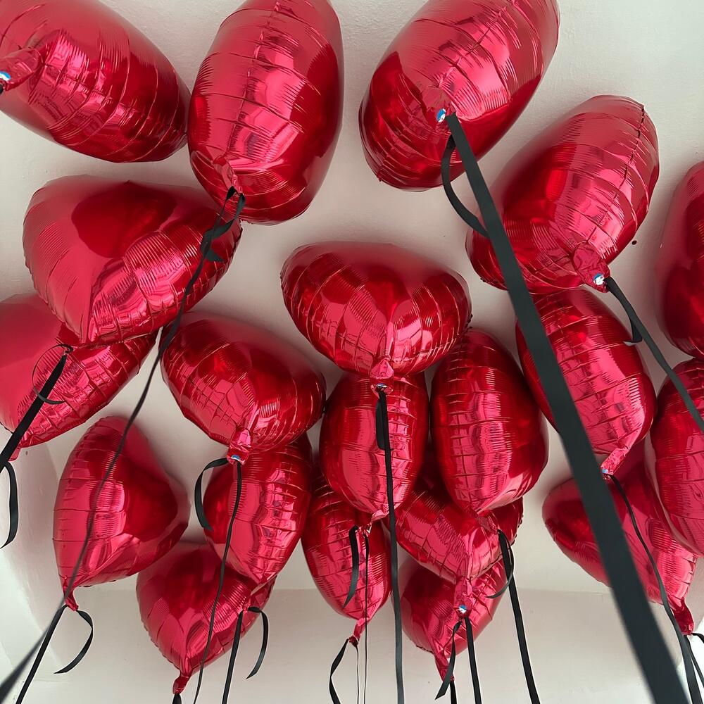 15 بالونًا على شكل قلوب حمراء معلقة بشرائط من الساتان للسقف