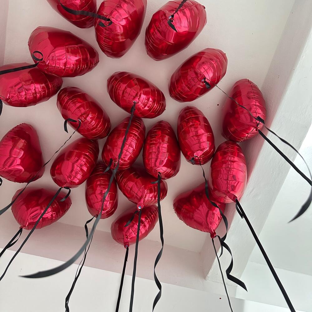 15 بالونًا على شكل قلوب حمراء معلقة بشرائط من الساتان للسقف