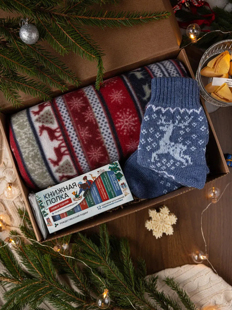 Подарочный набор к Новому году, включающий плед, чай и шерстяные носки.