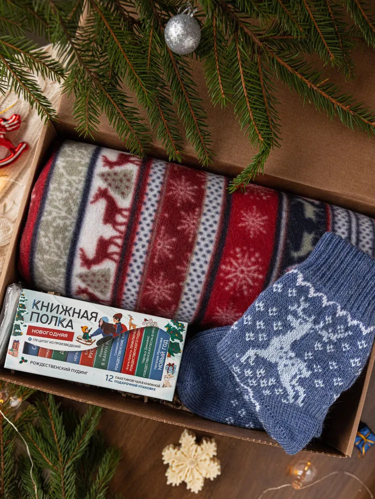 Подарочный набор к Новому году, включающий плед, чай и шерстяные носки.